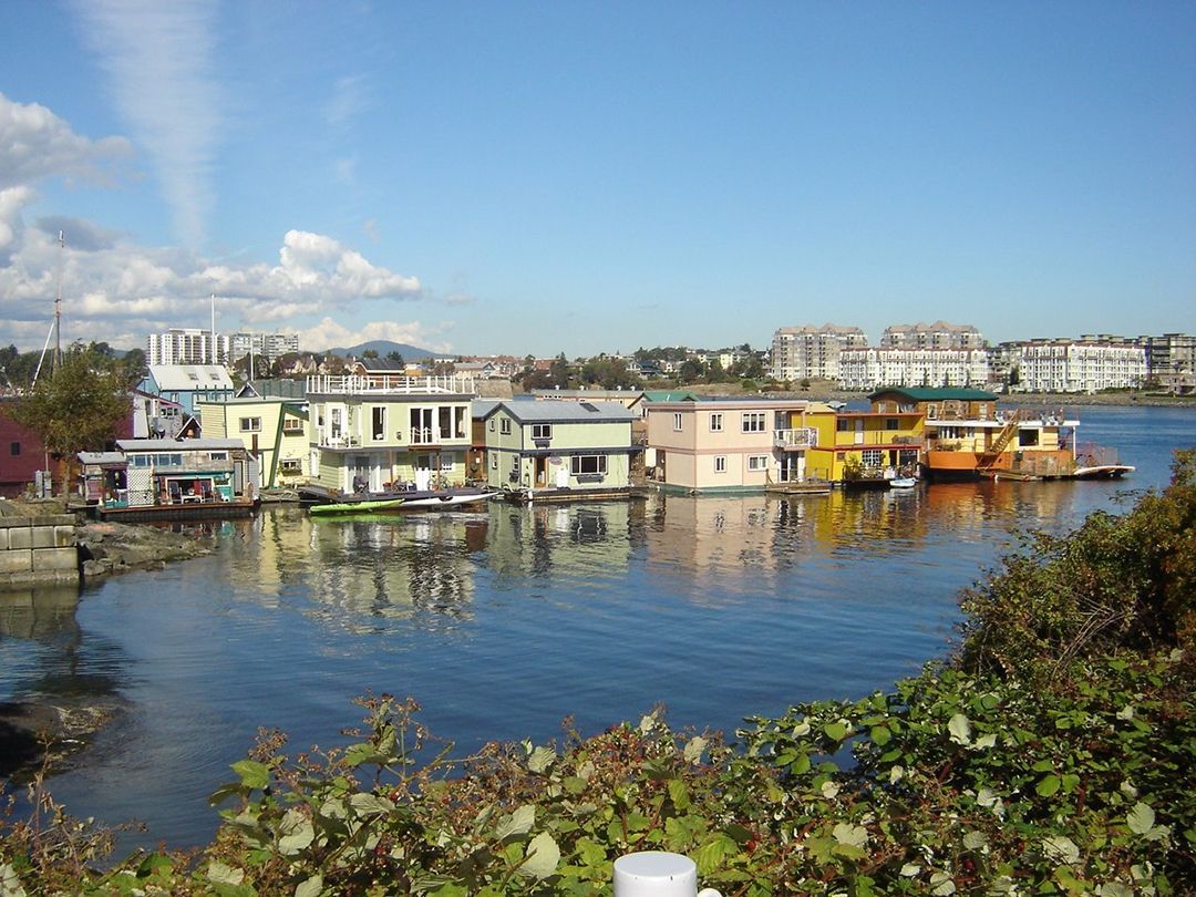 A group of houses are floating on top of a body of water.