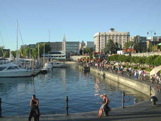 A group of people are standing on a pier next to a body of water.