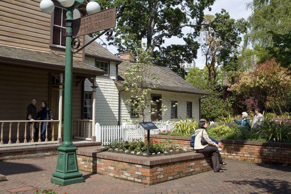 A woman is sitting on a bench in front of a building.