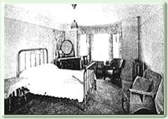 A black and white photo of a bedroom with a bed and chairs.