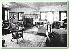 A black and white photo of a living room with furniture and a fireplace.