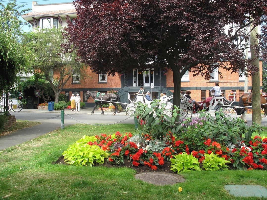 A park with flowers and trees in front of a brick building