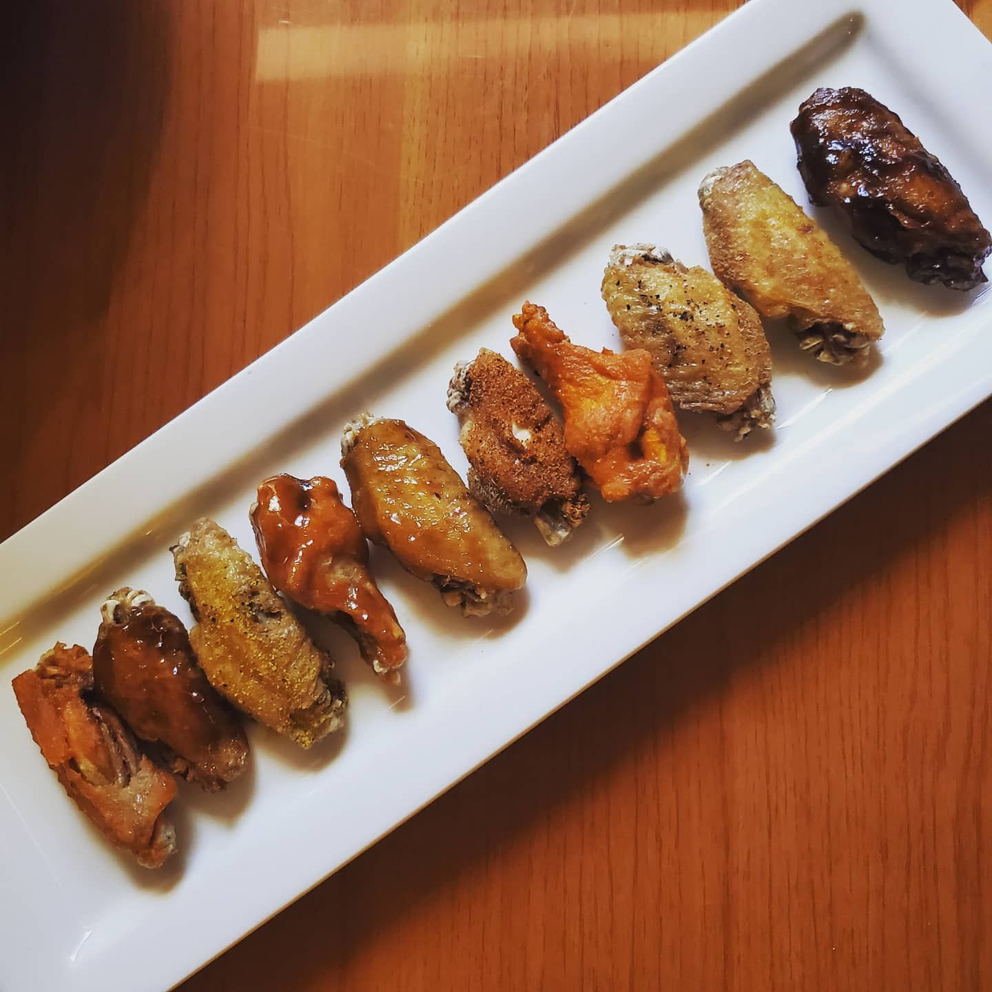 A row of chicken wings on a white plate