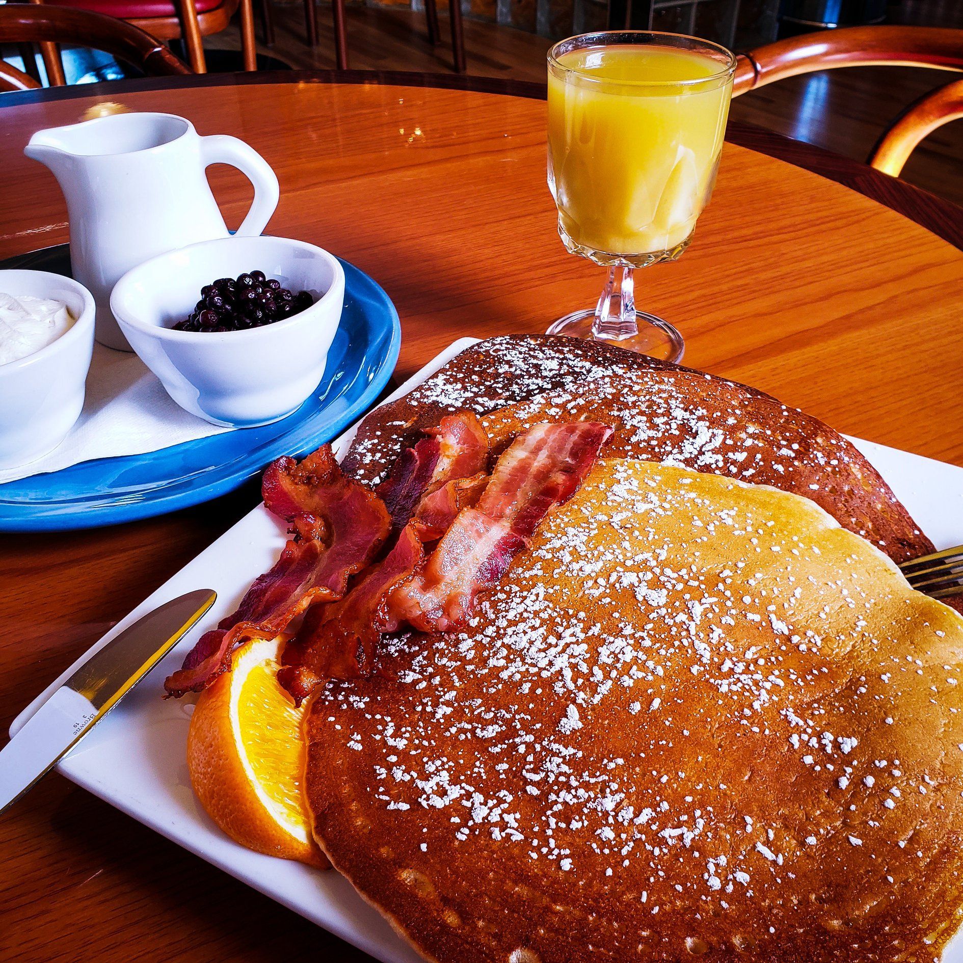 A plate of pancakes with bacon and a glass of orange juice