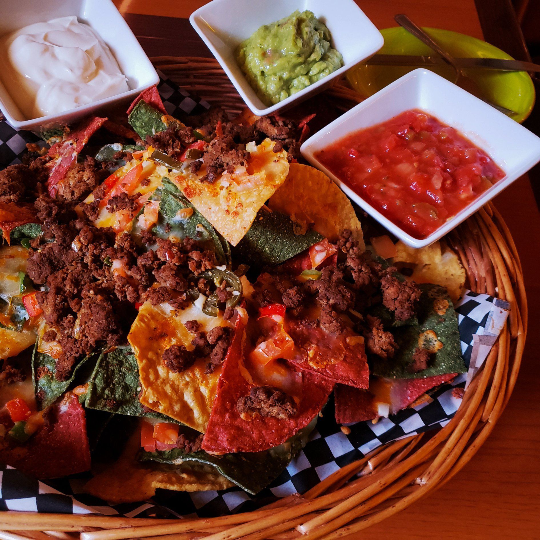 A basket of nachos with salsa guacamole and sour cream