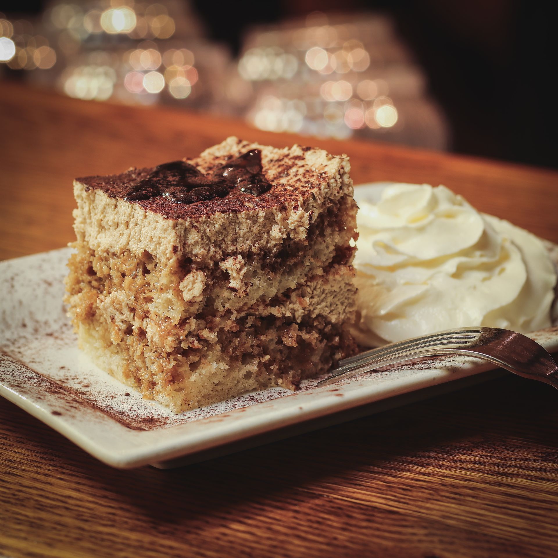 A piece of cake with whipped cream on a plate with a fork