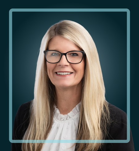 Woman wearing glasses, smiling, with long blonde hair, inside a blue border.