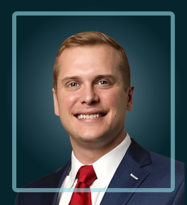 Man in suit and red tie smiling, inside a blue square frame against a dark blue background.