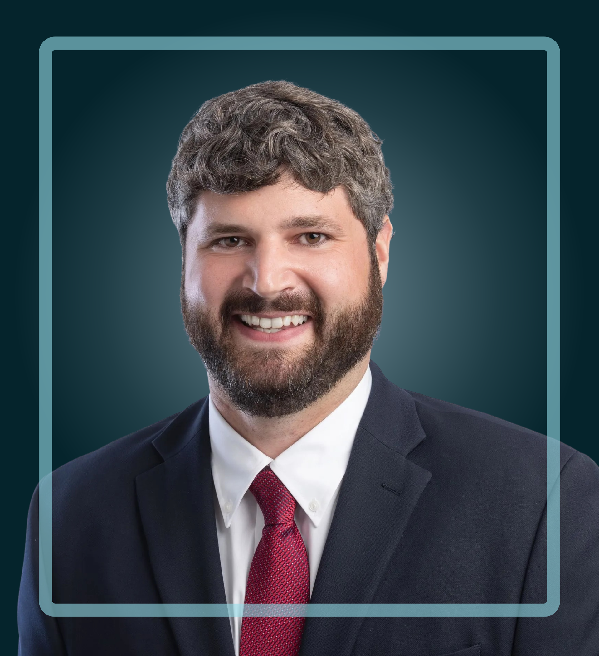 Man in a suit smiles, dark blue background, light blue border.