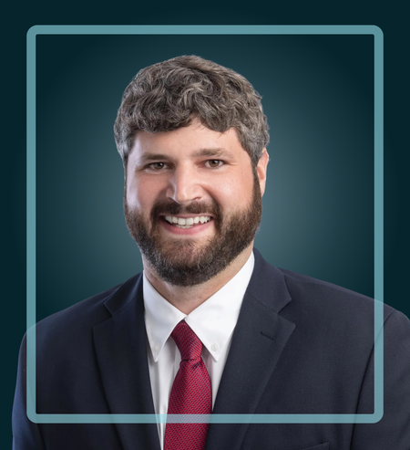 Man in a suit smiles, dark blue background, light blue border.