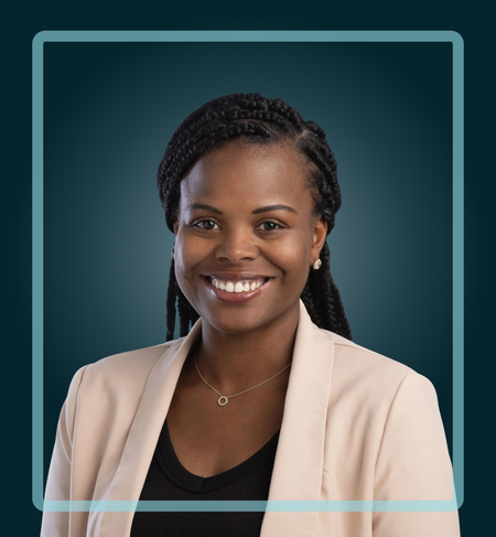 Woman with braided hair, smiling, wearing a cream blazer and a black shirt, in front of a teal background.