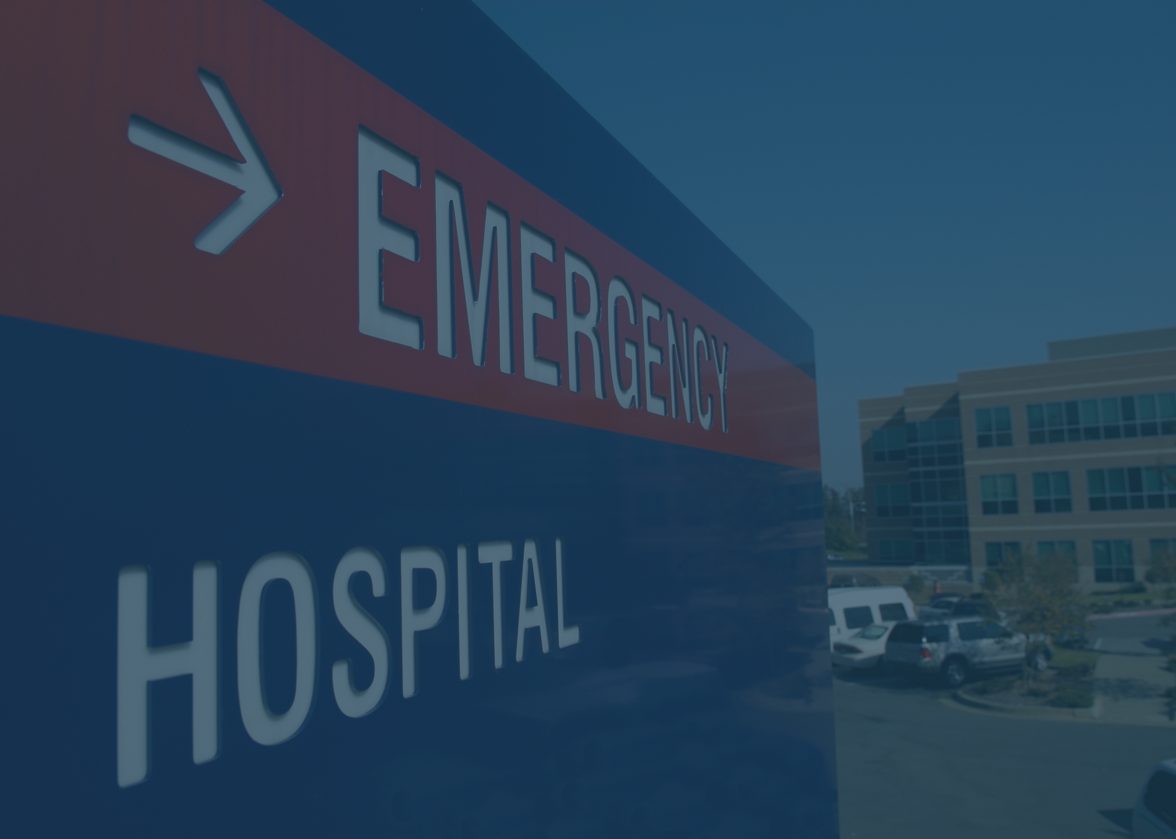 Hospital emergency sign with arrow pointing towards building.
