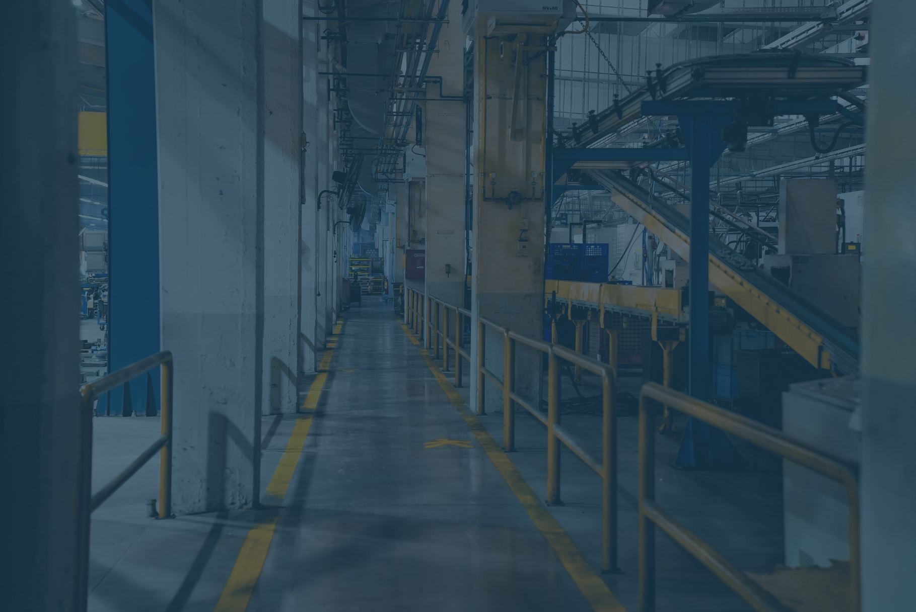 Industrial hallway with yellow lines, metal railings, and machinery.