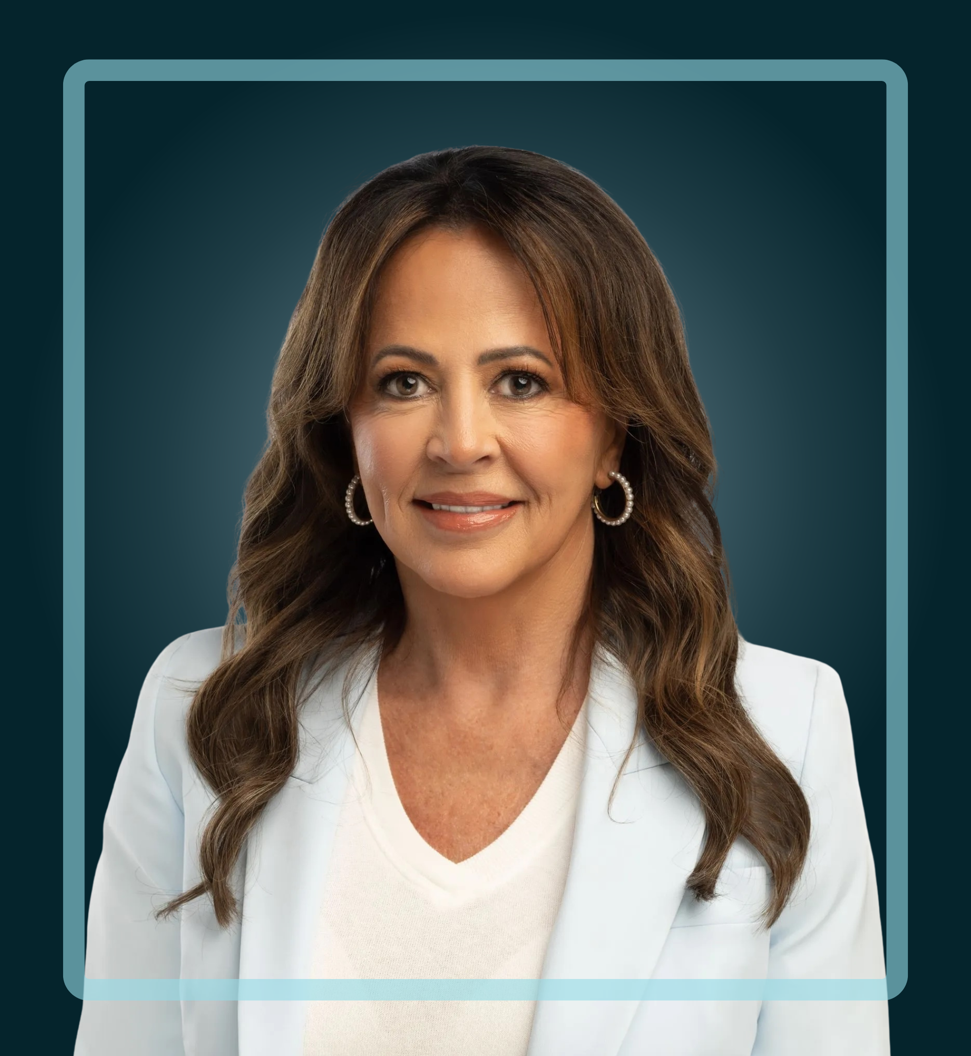 Woman with brown hair smiles, wearing a light blue blazer and hoop earrings, against a teal background.