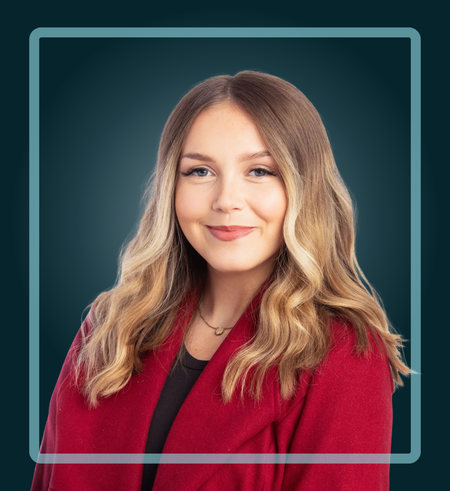 Woman with long blonde wavy hair smiles wearing a red sweater against a dark teal background.