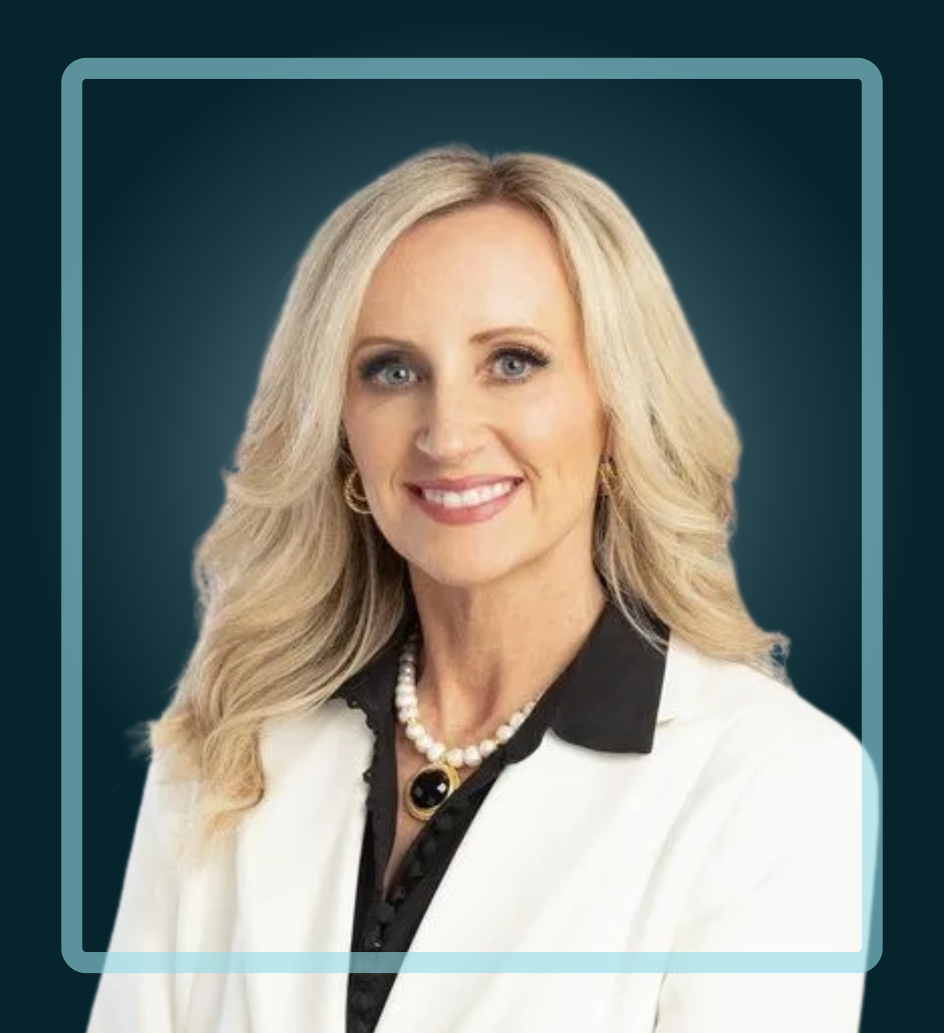 Woman in a white blazer smiles, pearl necklace.