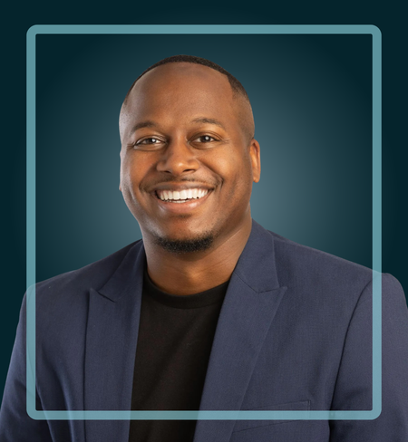 Smiling man in a navy blazer against a teal background, enclosed in a light blue square.