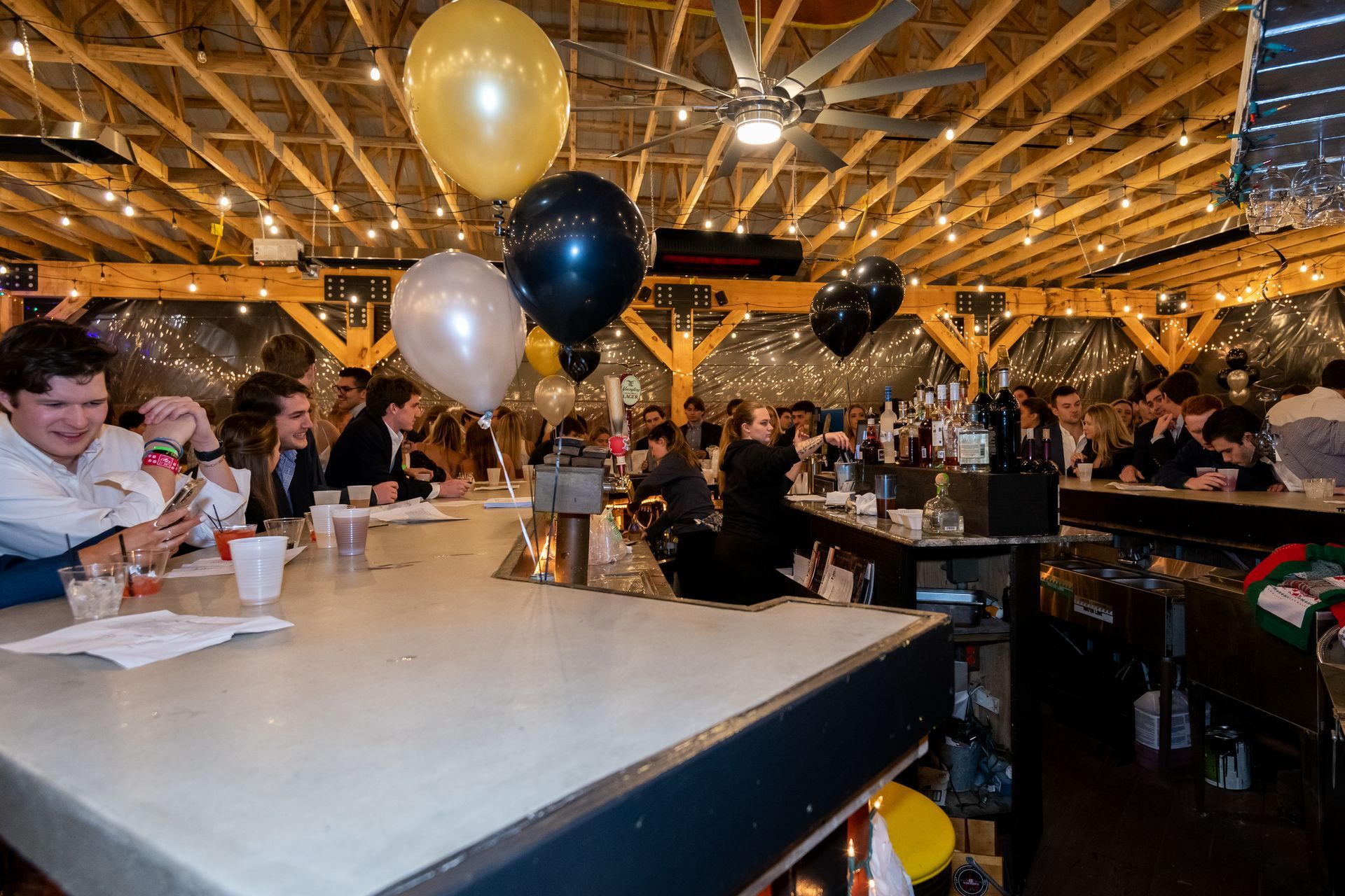 A group of people are sitting at a table in a restaurant with balloons hanging from the ceiling.