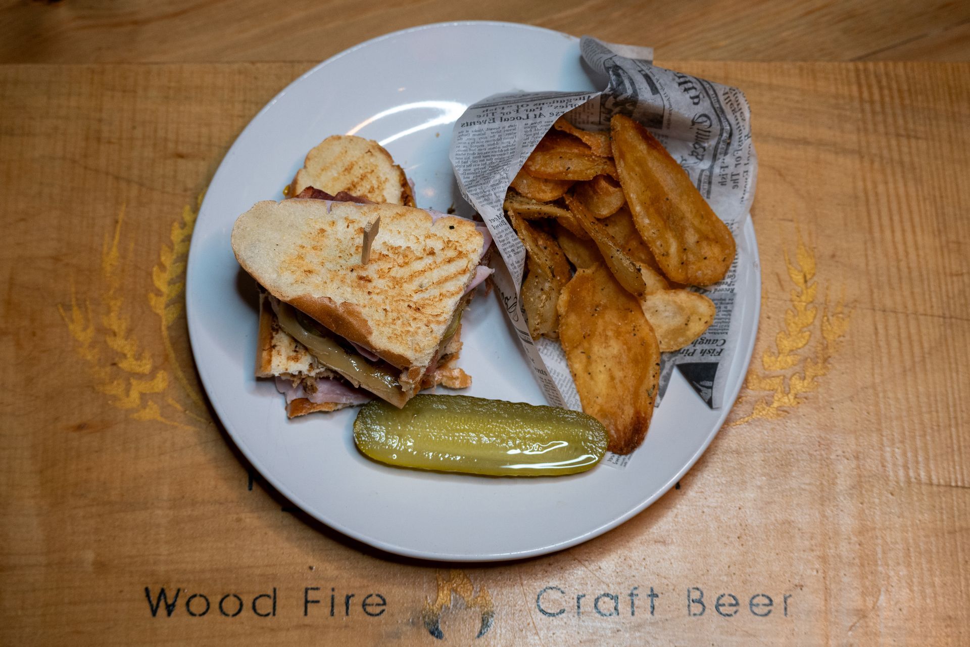 a white plate topped with a sandwich and chips on a wooden table .