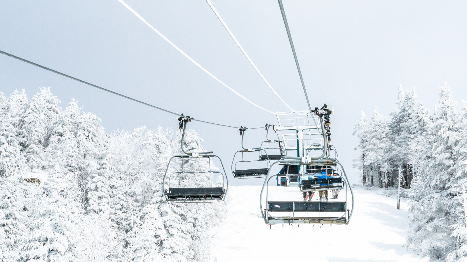 A ski lift is going down a snow covered slope.