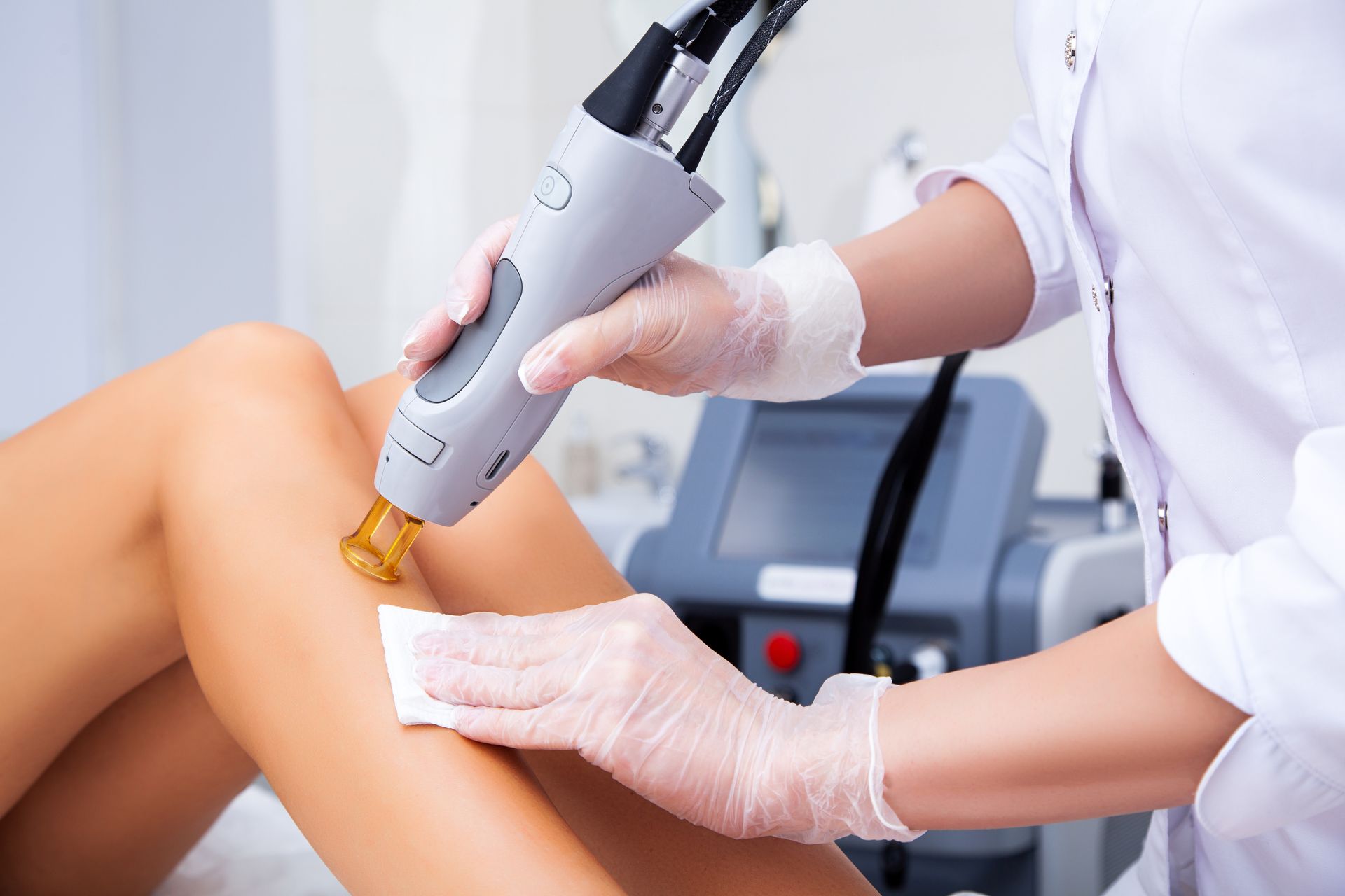 A woman is getting laser hair removal on her legs.