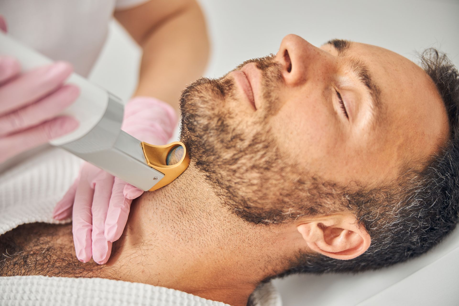 A man is getting laser hair removal in the beard area.