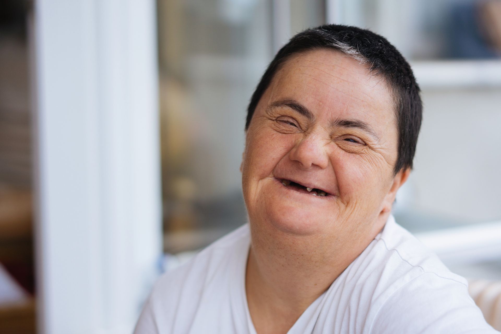 A woman with down syndrome is smiling and looking at the camera.