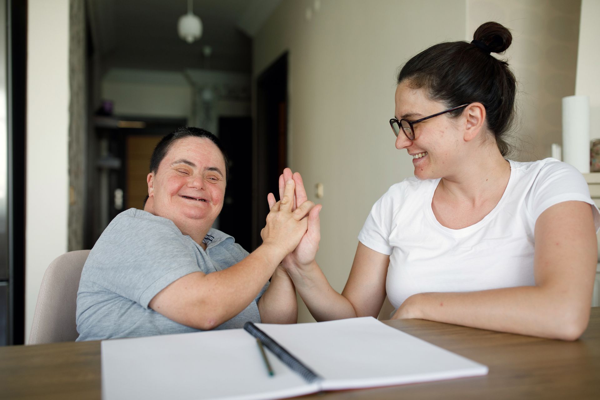 A woman and a boy with down syndrome are giving each other a high five.