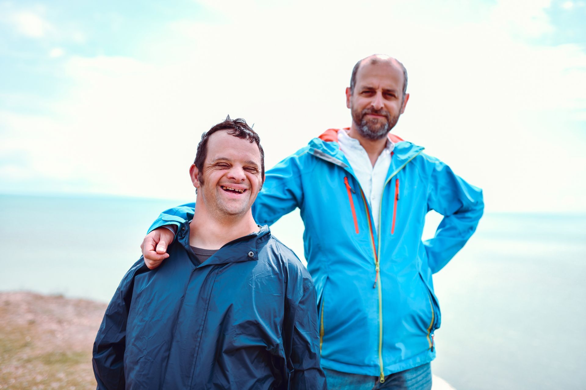 Two men are standing next to each other on the beach.