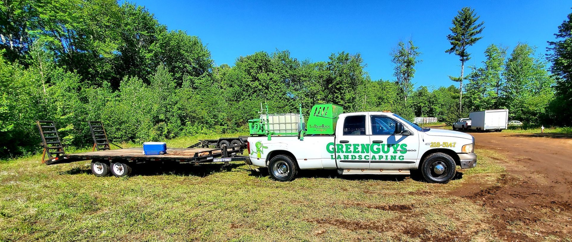 A truck with a trailer attached to it is parked in a field.