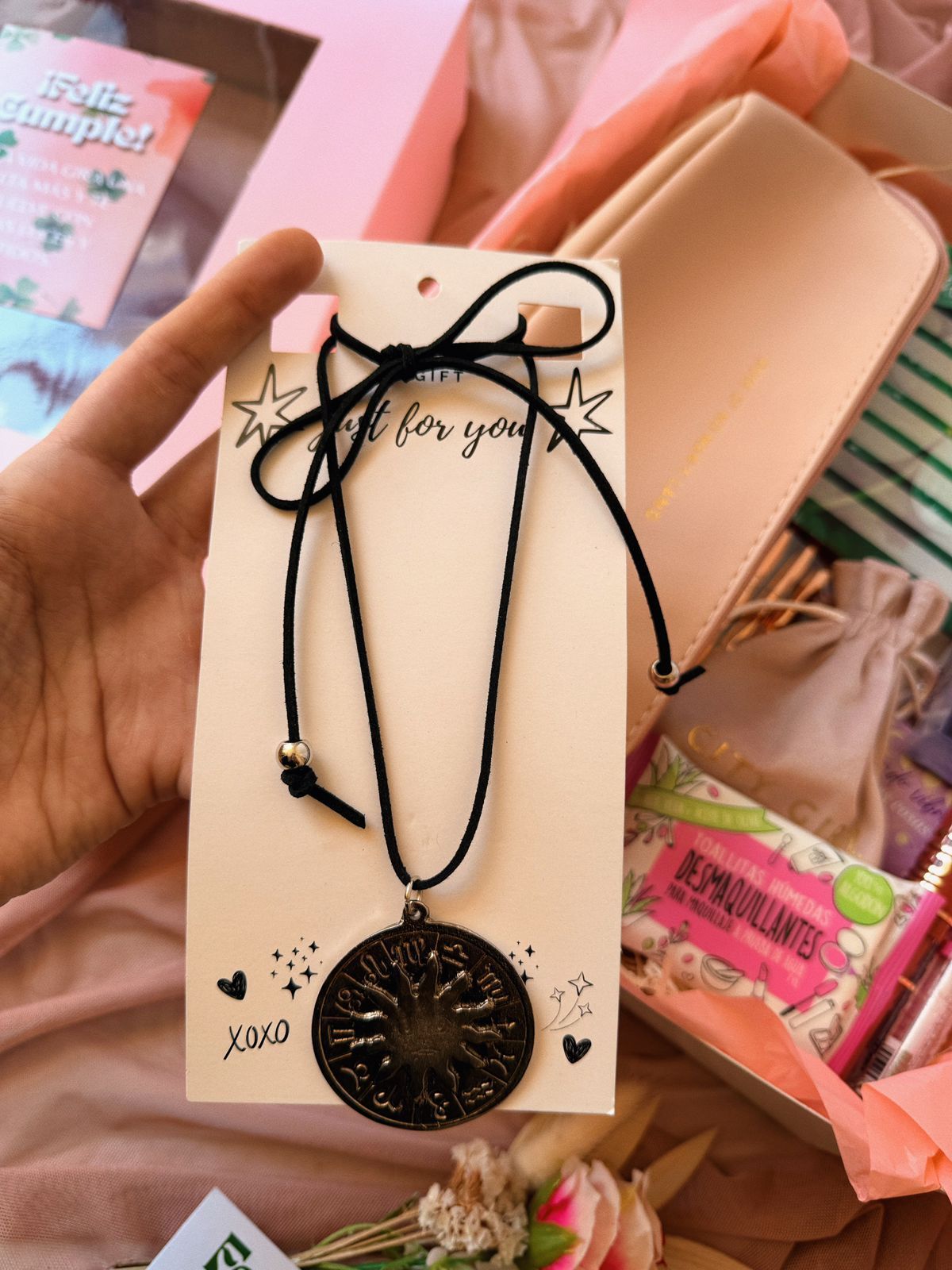 Una caja rosa con una cinta verde y flores dentro.