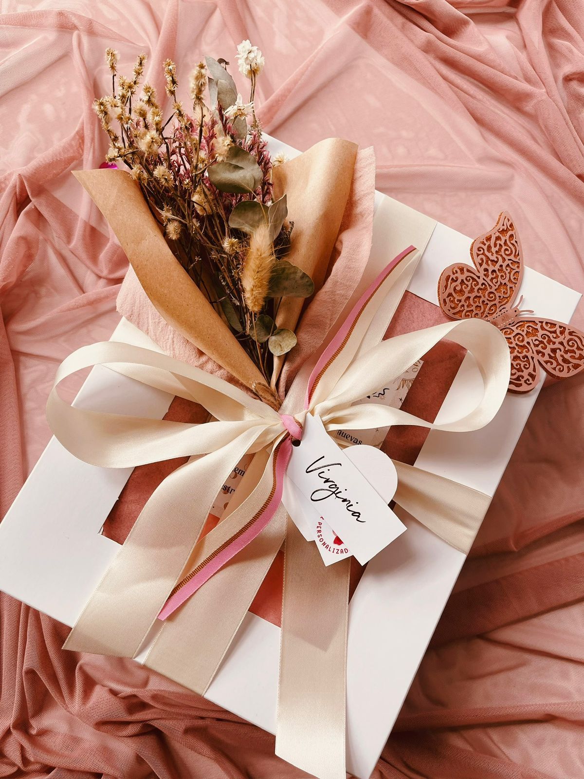 Una persona sostiene una caja de regalo con una tarjeta y una botella de vino.