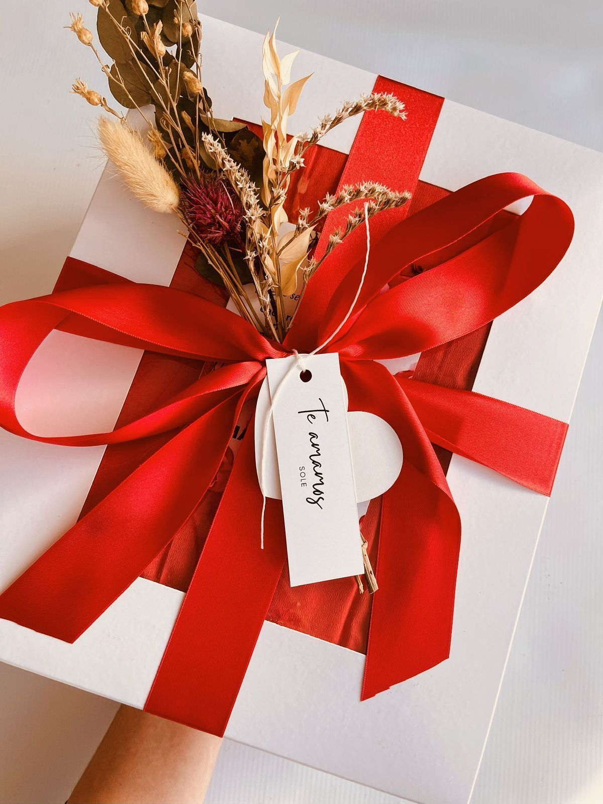 Una persona sostiene una caja de regalo con una cinta roja y una etiqueta que dice para siempre.
