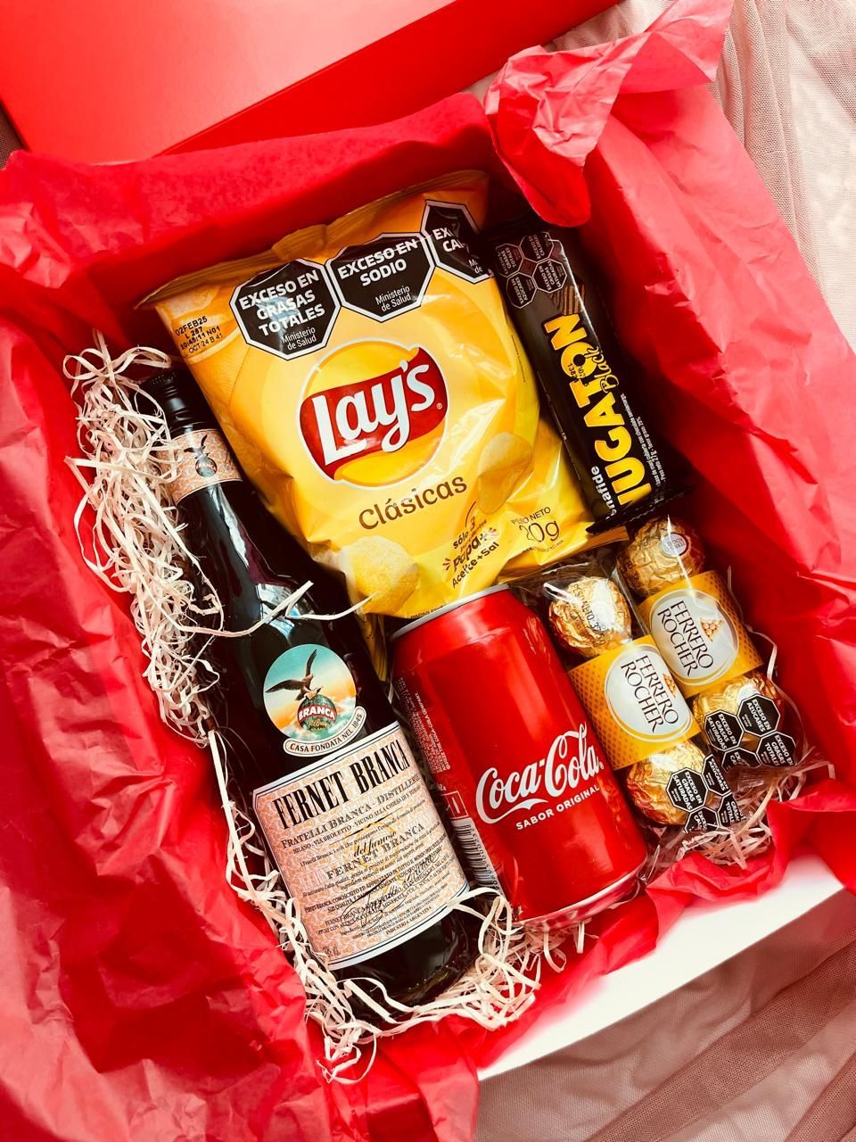 Una caja llena de lays, coca cola y otros bocadillos.