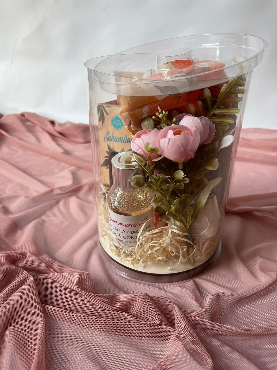 Un cachorro está sentado en una mesa junto a una tarjeta y flores.