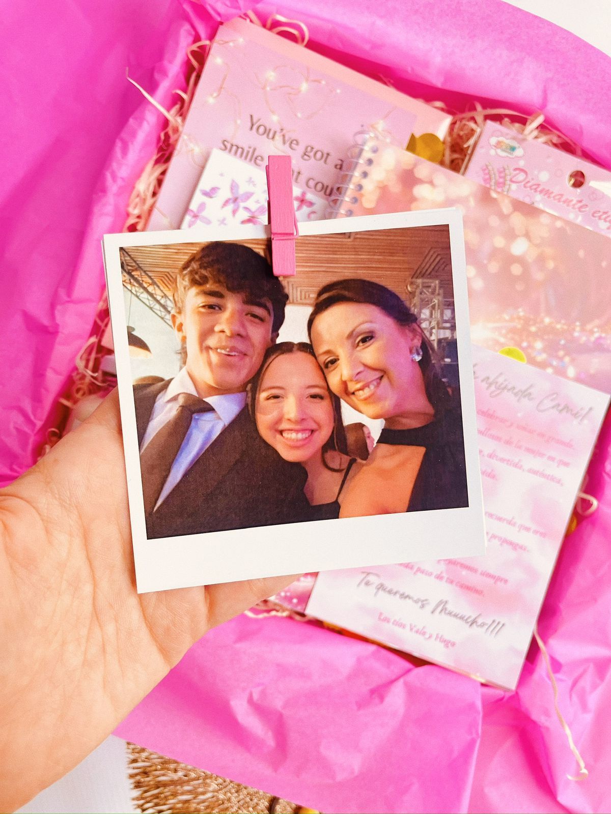 Una caja rosa llena de un cuaderno, una vela y una pulsera.