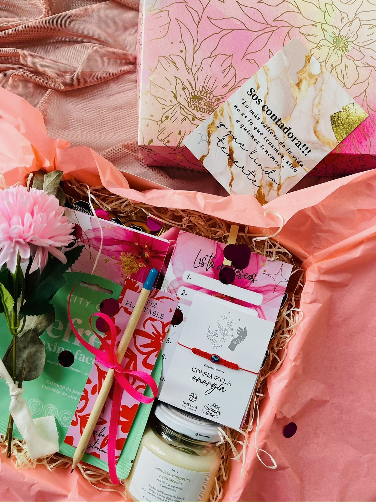 Una caja de regalo llena de flores, velas, cuadernos y otros artículos.