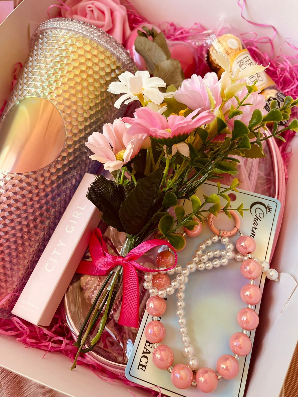 Una caja llena de flores, una pulsera y una taza