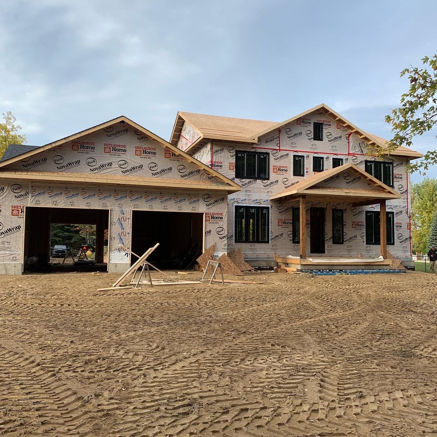 A large house is being built in a dirt field.