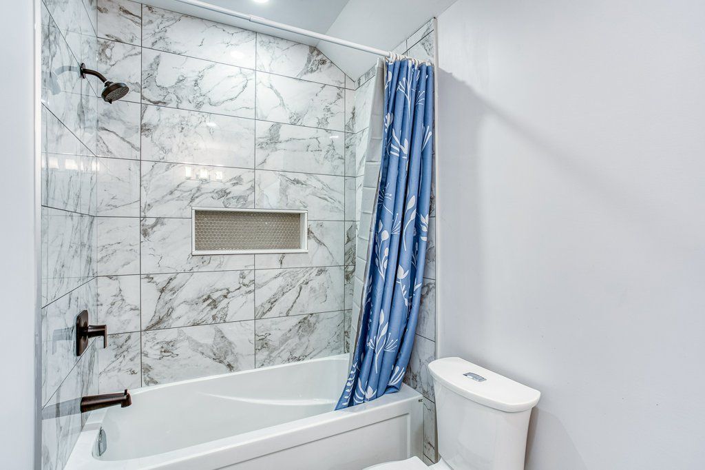 A bathroom with a tub , toilet and shower.