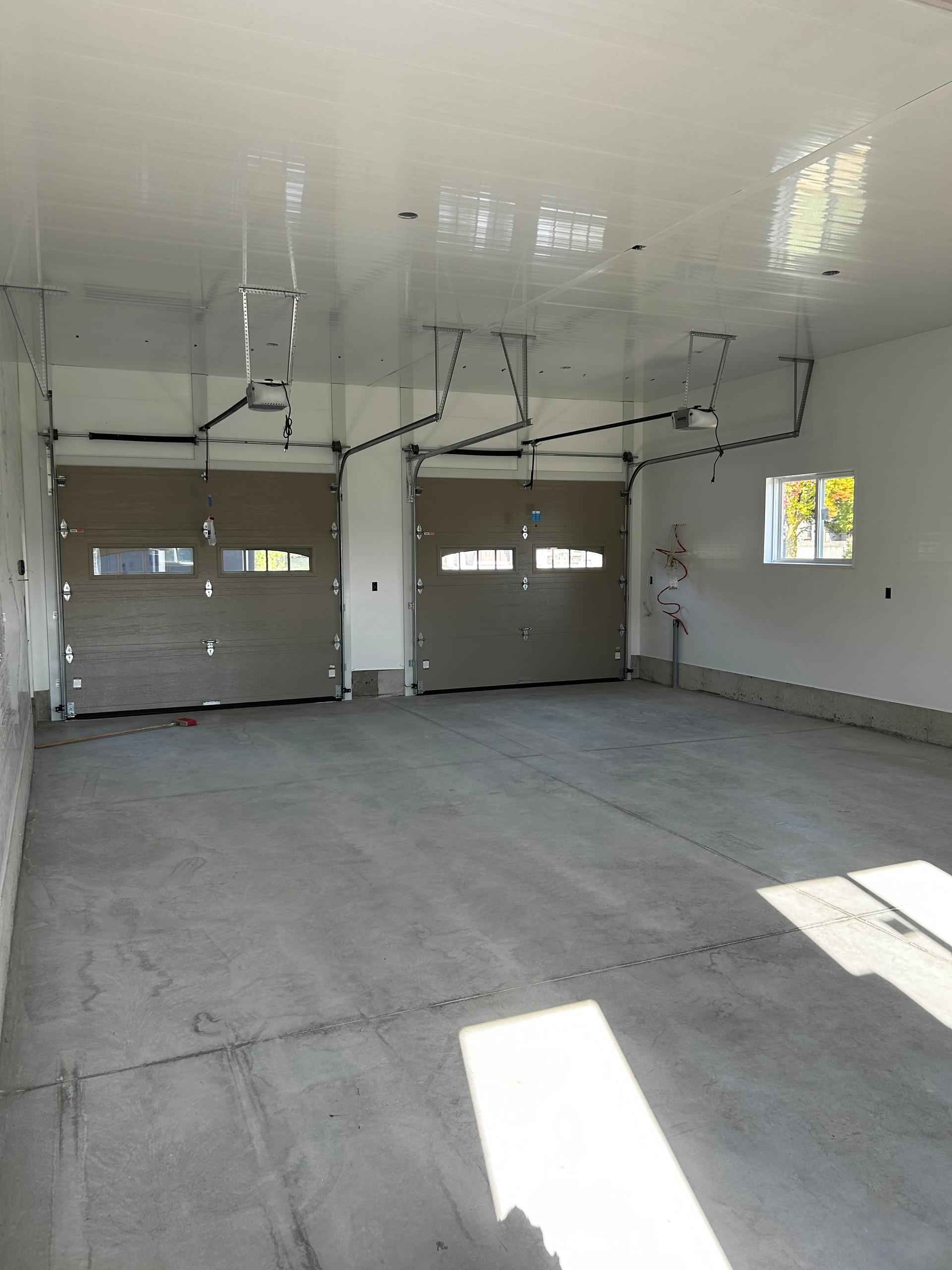 An empty garage with two garage doors and a window