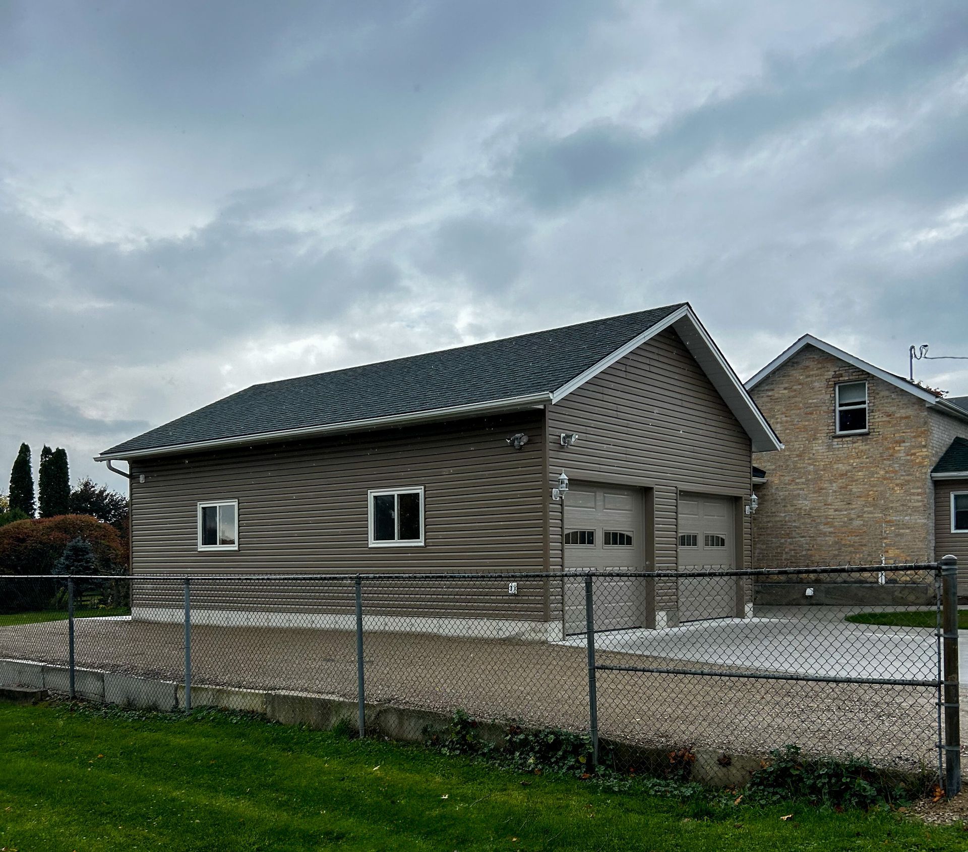 A house with a green roof is behind a chain link fence