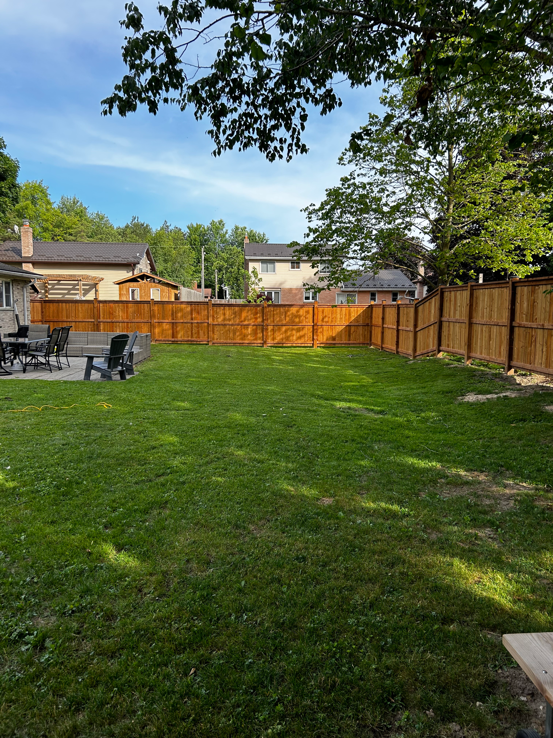 A backyard with a wooden fence and a fire pit.