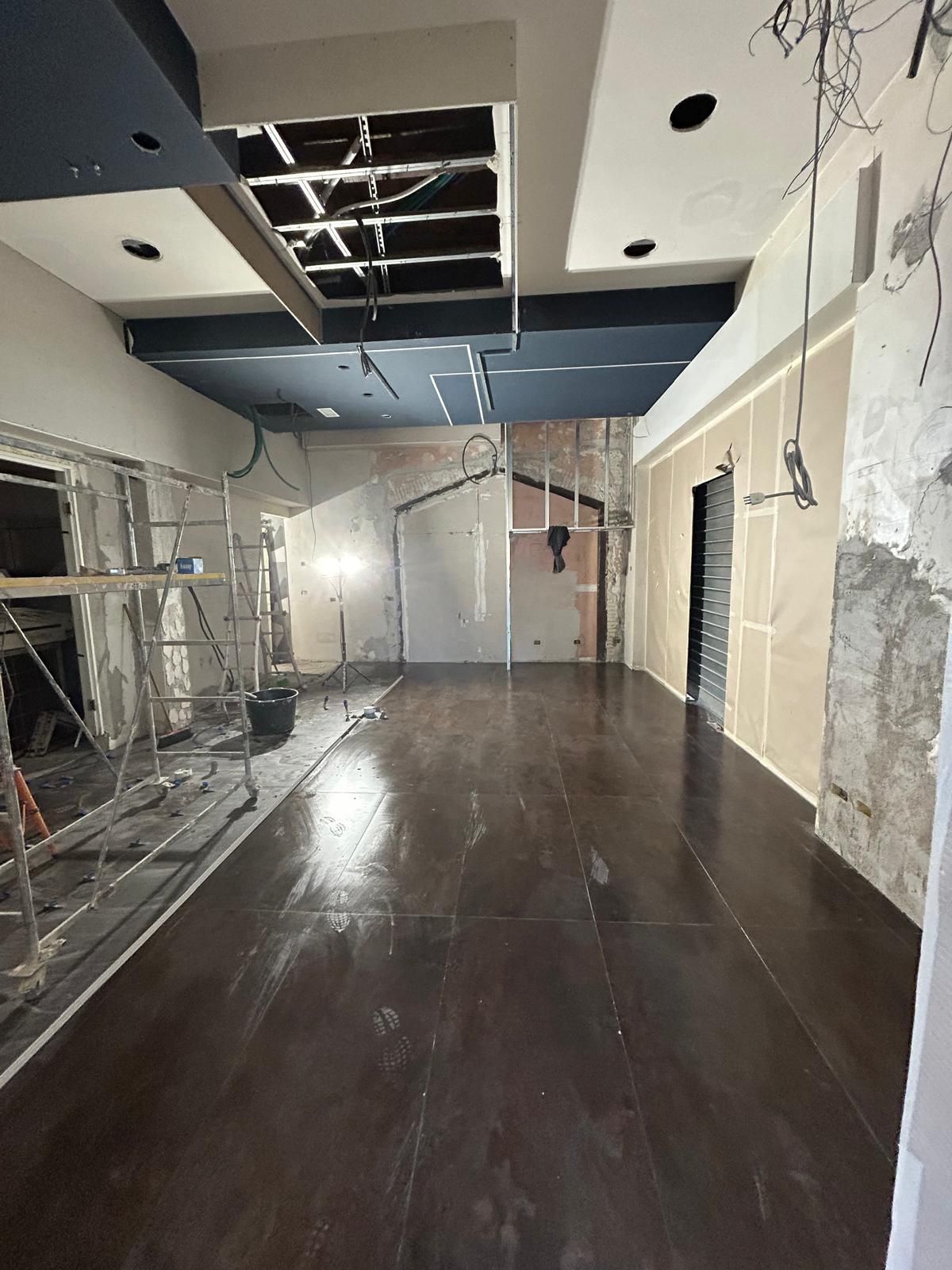 Interno durante la ristrutturazione; pavimento in legno scuro, soffitto a vista, impalcature, pareti grezze.