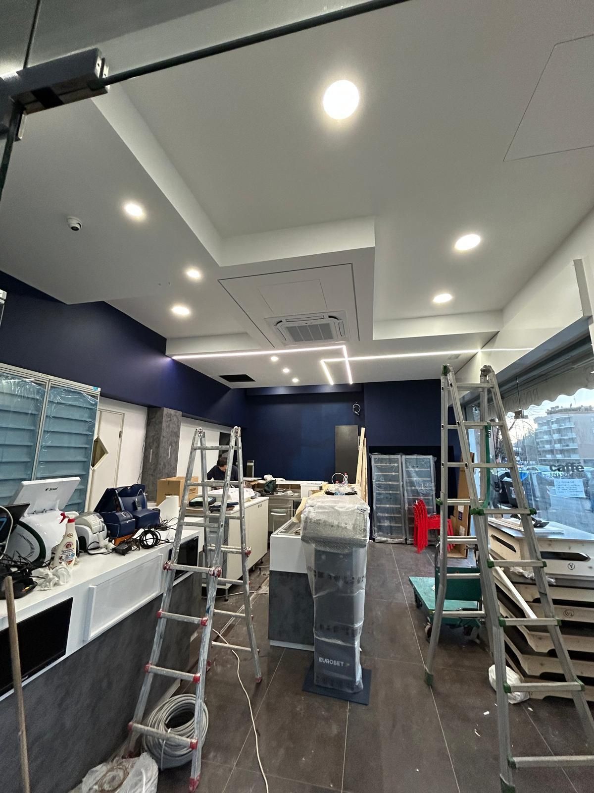 Negozio interno in costruzione con scale, attrezzature e una combinazione di colori blu e bianco.