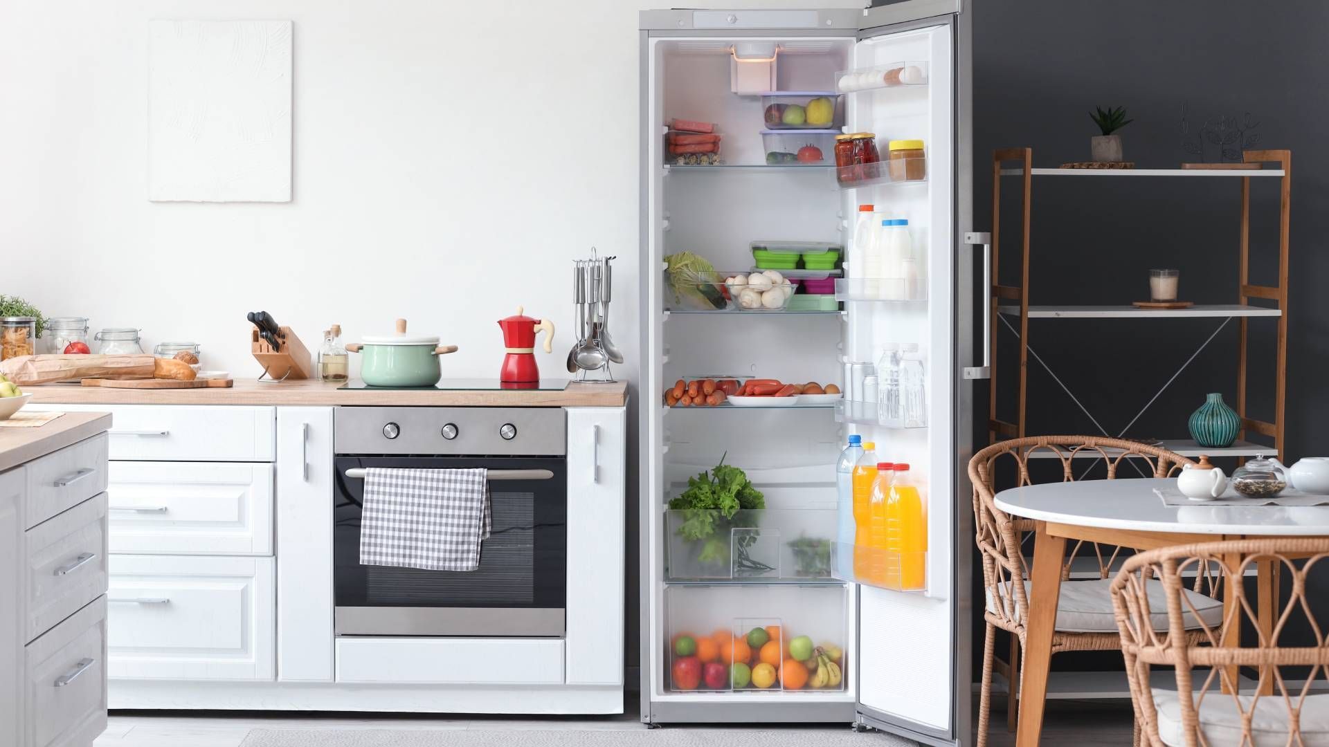A kitchen with a refrigerator , oven , table and chairs.