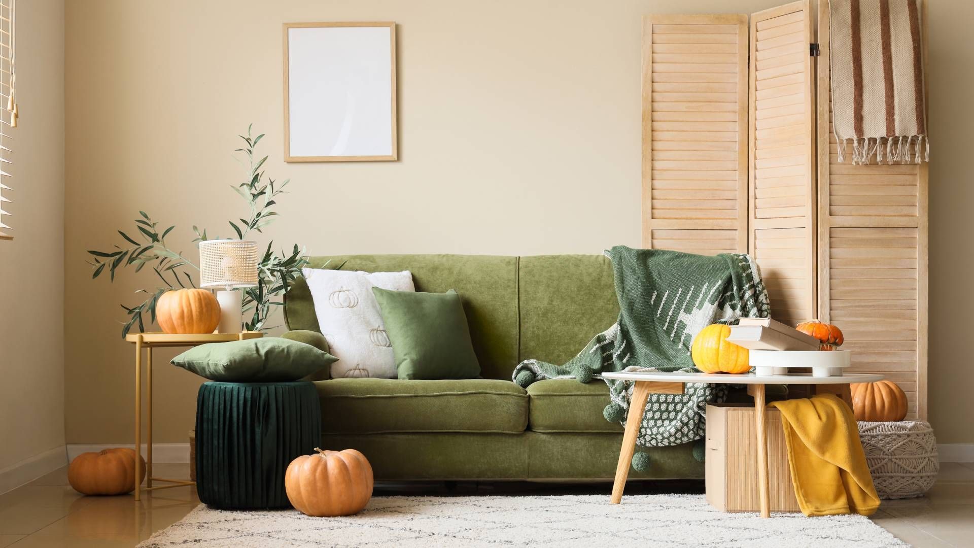 A living room with a green couch and pumpkins on the floor.