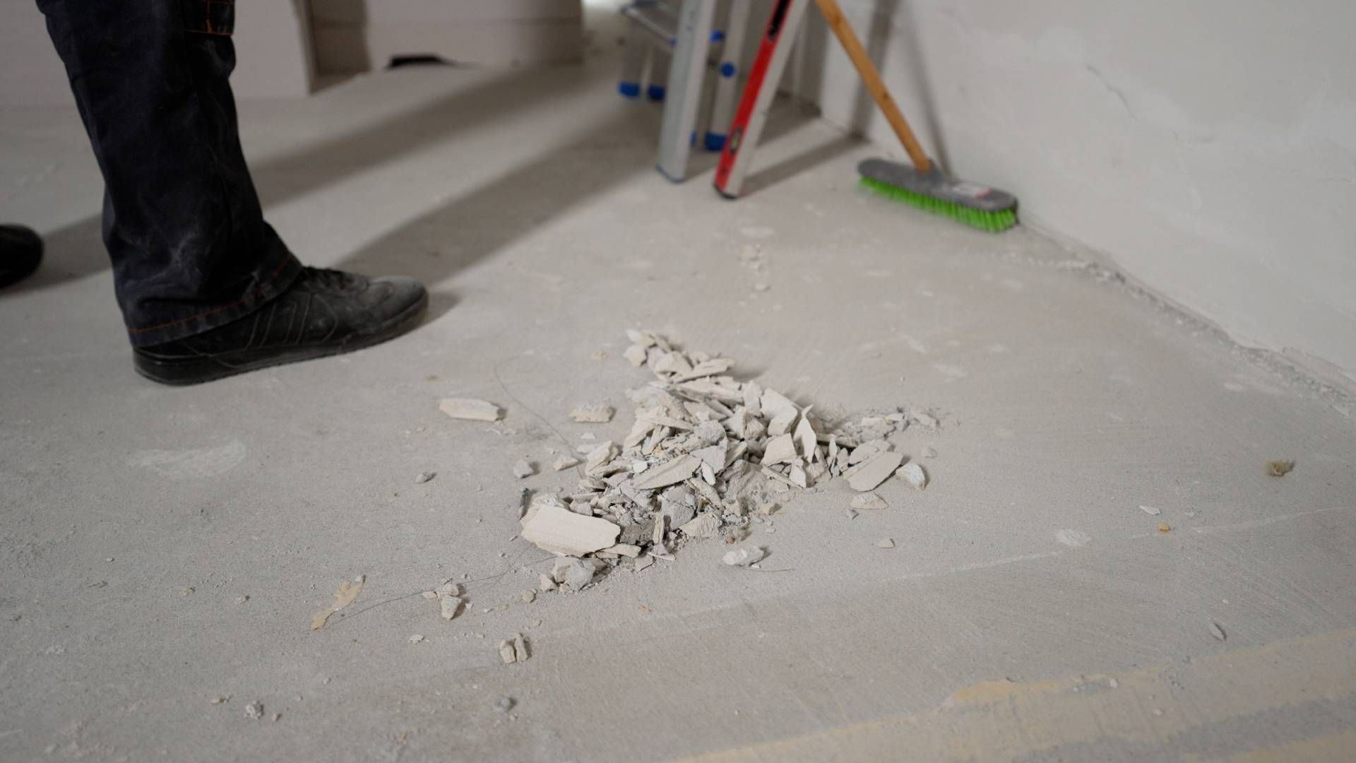 A person is standing next to a pile of concrete on the floor.