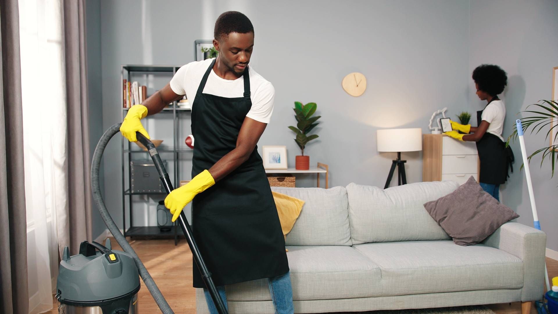 A man is cleaning a living room with a vacuum cleaner.