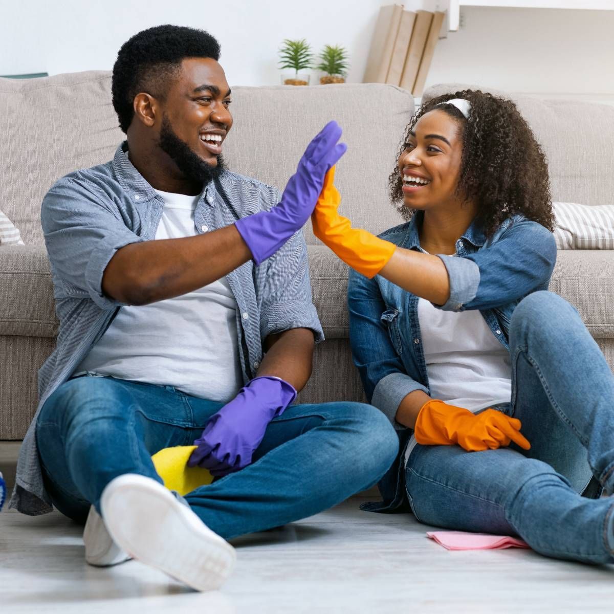 A man and a woman are sitting on the floor giving each other a high five.